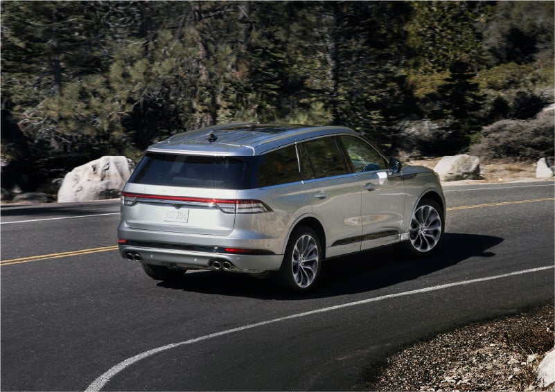 A 2023 Lincoln Aviator® Grand Touring model is shown being driven on a tight turn of a mountain road | Preston Lincoln in Hurlock MD